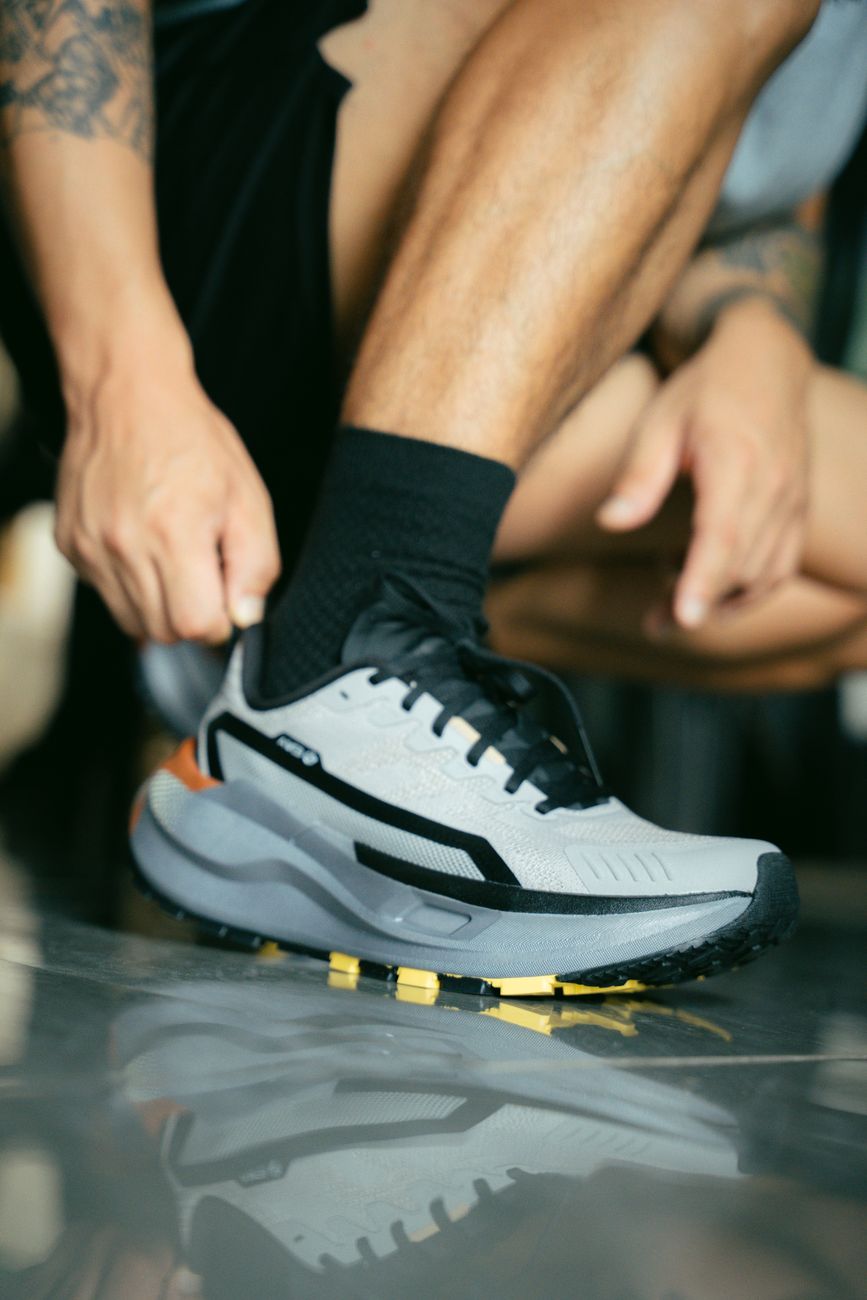 man tying running shoe on reflective floor